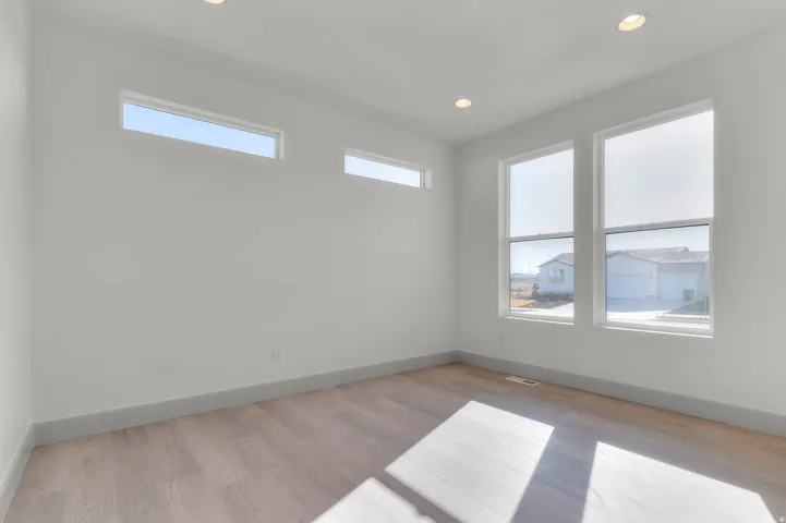 Room featuring wood-finish flooring, two large vertical windows, two horizontal transom windows, recessed lighting, and light gray baseboards