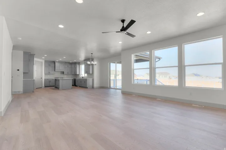 Expansive open-concept living space with light wood-finish flooring, recessed lighting, and a modern ceiling fan