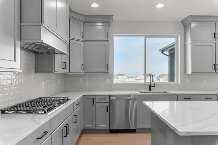Contemporary kitchen featuring gray shaker-style cabinetry, white countertops, a built-in gas range with range hood, and a stainless steel dishwasher