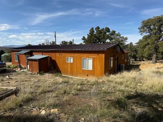 Property exterior featuring wood-paneled siding, a dark brown metal roof, and white-framed windows