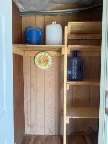 Utility storage area featuring wood-finish wall panels and wood-finish flooring