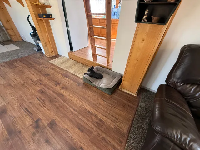 Wood-finish flooring throughout, complemented by a brown leather sofa