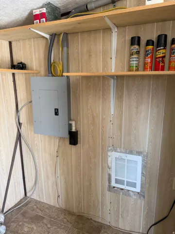 Utility area featuring wood-panel walls, a main electrical panel, and a wall-mounted heater