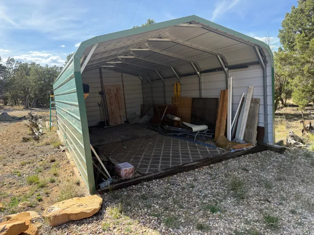 Green metal utility structure featuring an open front with a gravel and paver-style flooring
