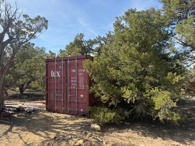 Red cargo container on a natural landscape with mature trees