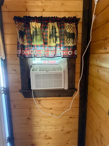 Window-mounted air conditioning unit with a dark-stained wood window frame