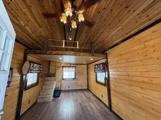 Interior featuring wood-finish paneling throughout, a wood-finish plank ceiling, and a prominent wood-beam loft structure