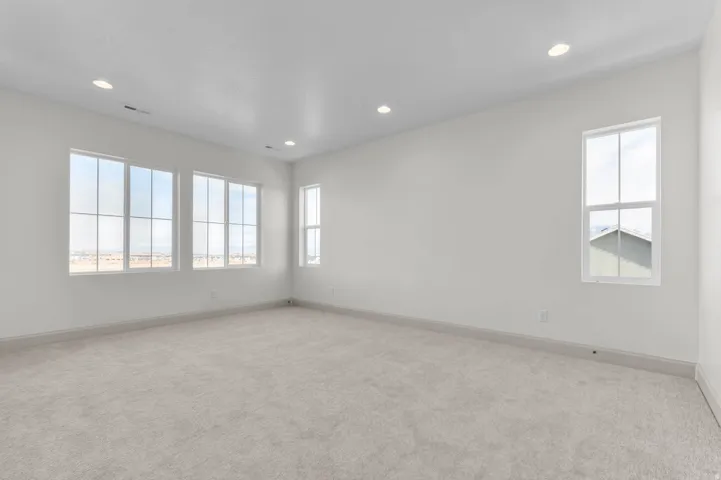 Spacious room featuring light-colored carpeting, white painted walls, and recessed lighting