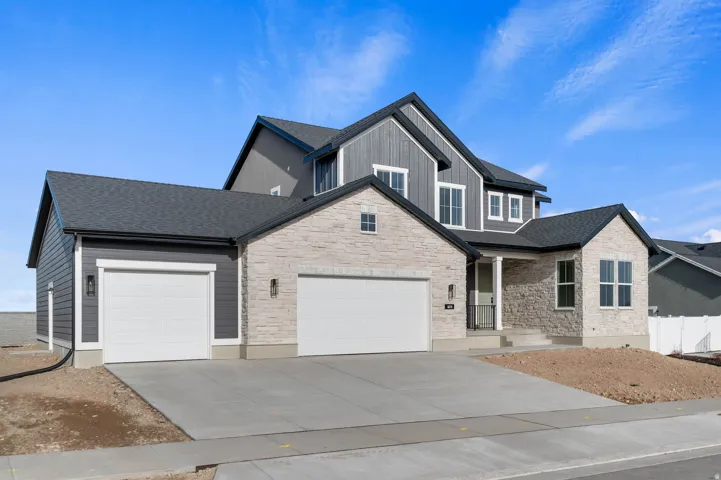 Modern dwelling featuring a stone and siding exterior, a two-car garage, an additional single-car garage, a covered entry, and multiple windows with white trim