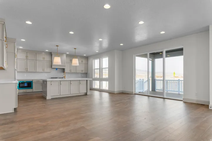 Open-concept living space featuring wood-finish flooring, recessed lighting, and a modern kitchen with light-toned cabinetry