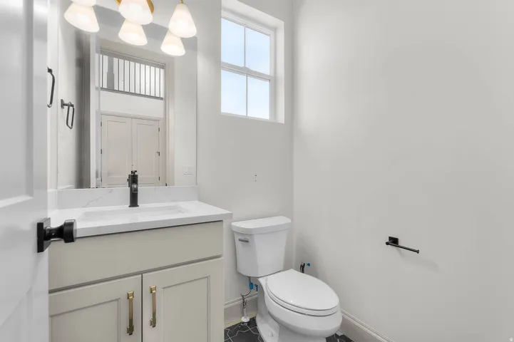Vanity featuring a white countertop with integrated sink, matte black faucet, and brass-finished hardware