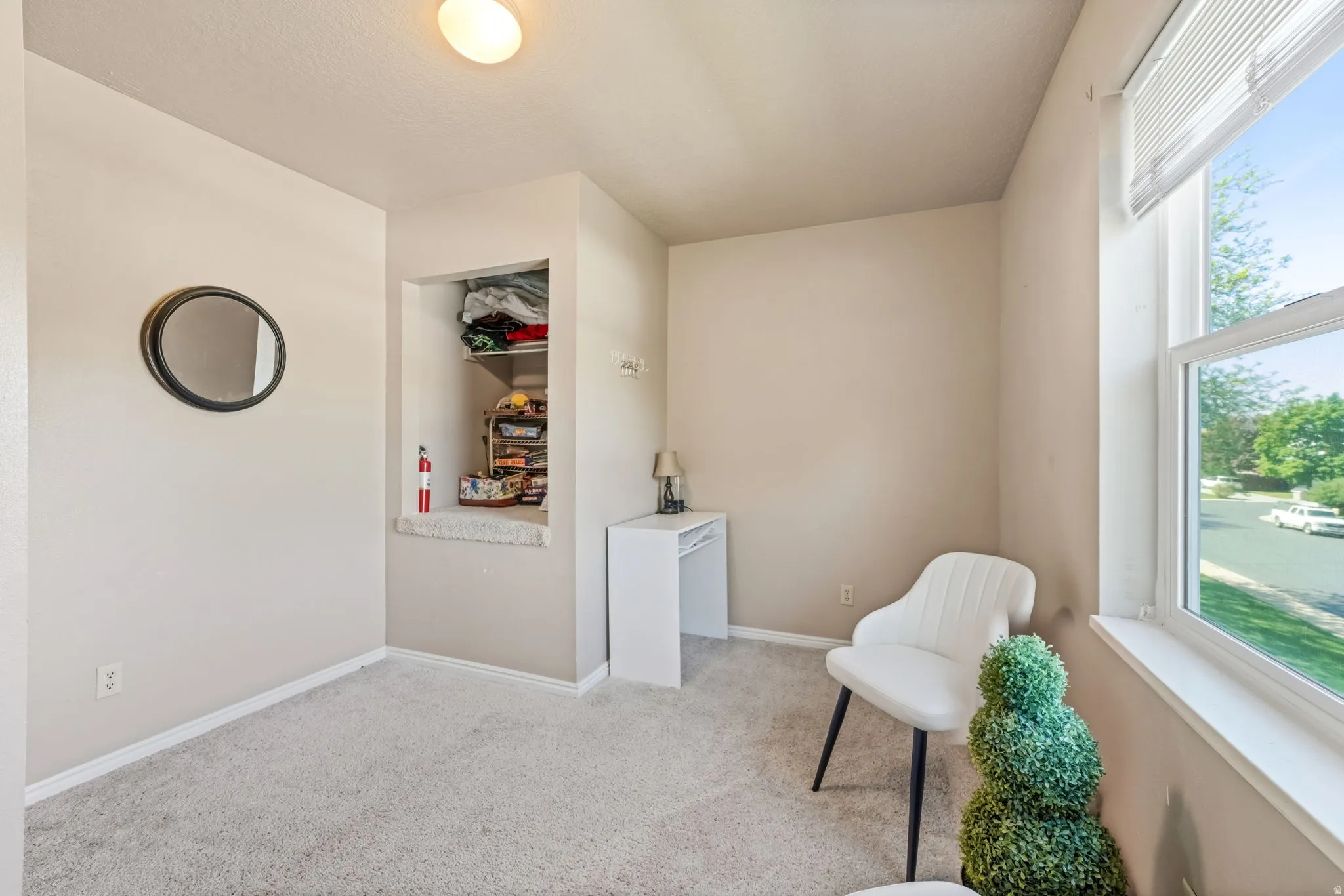 Room featuring plush carpet flooring, a recessed wall niche with built-in shelving, and a large window with a white frame