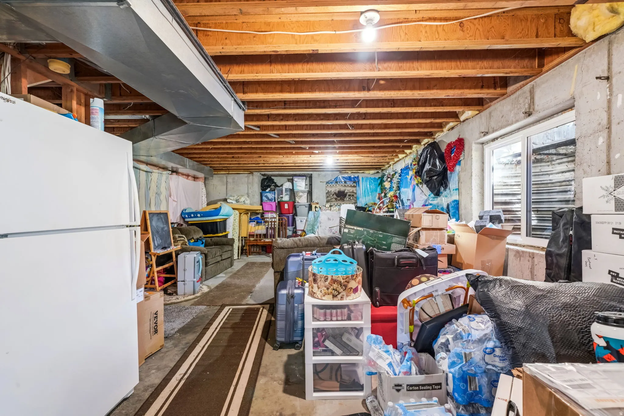 Unfinished basement with exposed ceiling joists, concrete foundation walls, and a visible HVAC duct system