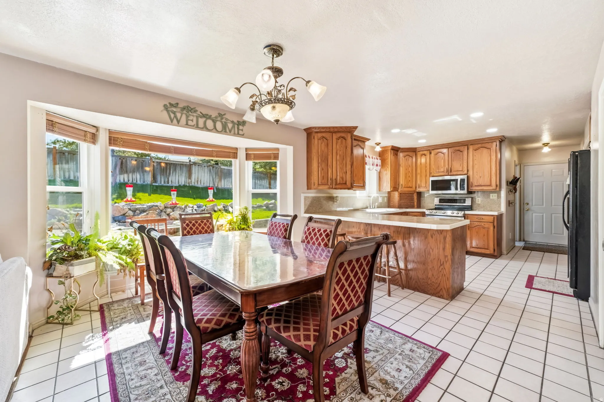 Kitchen with wood-finish cabinetry, stainless steel appliances, and a central island with countertop seating