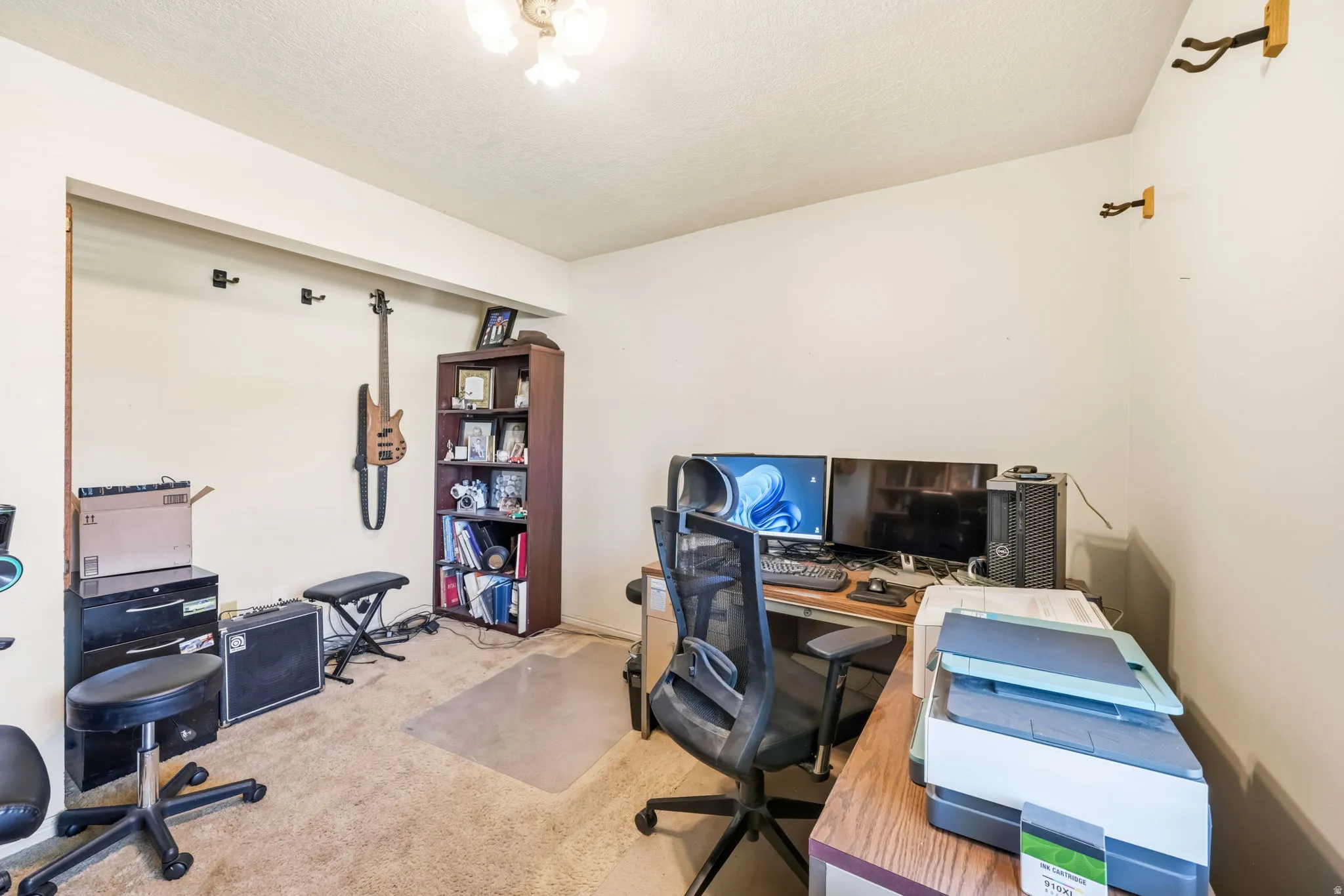Carpeted interior room with a built-in shelving unit, a wood-finish desk, and a ceiling-mounted light fixture
