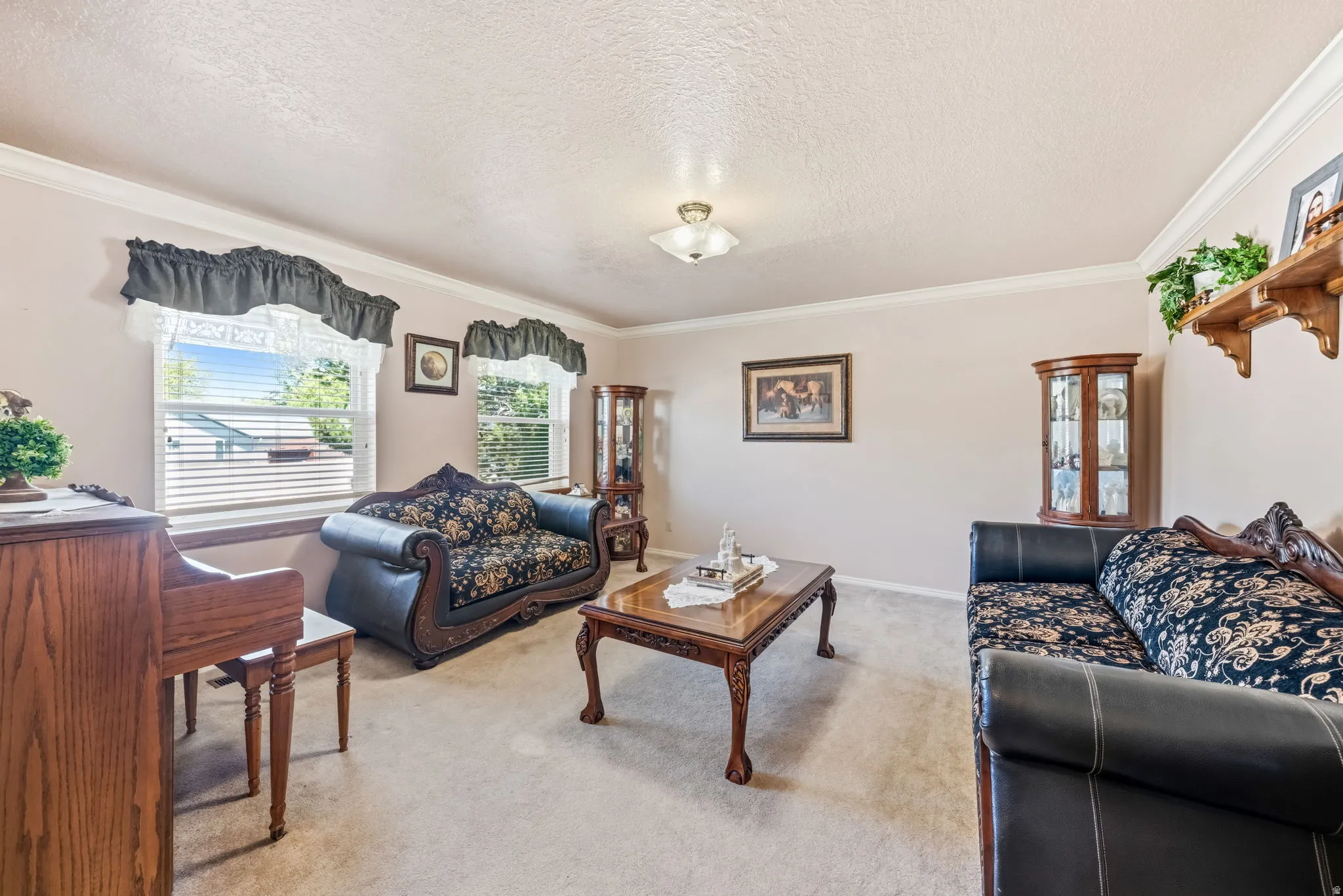 Bright living area featuring light-colored carpet, crown molding, and two large windows with blinds
