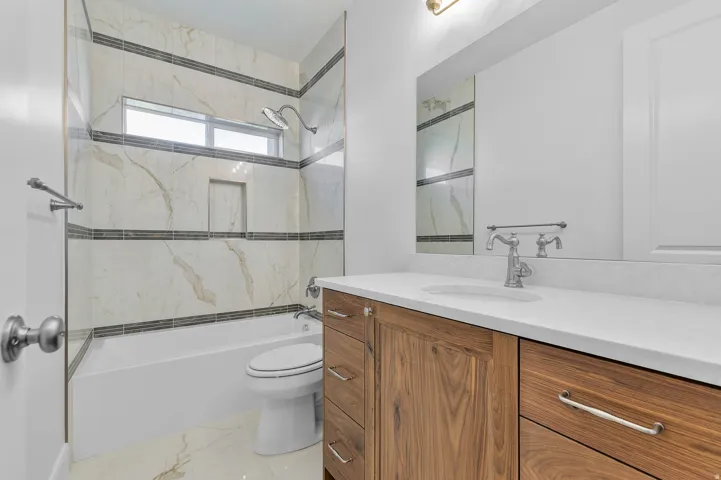 Bathroom featuring a wood-finish vanity with a white countertop, an undermount sink, and a framed mirror