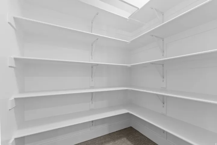 Expansive pantry featuring white shelving, multiple storage tiers, and a skylight