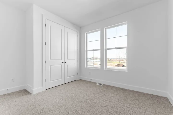 Room featuring a neutral wall color, two windows with grid patterns, and neutral-toned carpeting