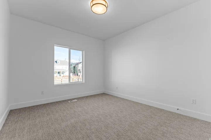 Bright room featuring a large window, neutral carpeting, white baseboards, and a contemporary ceiling fixture