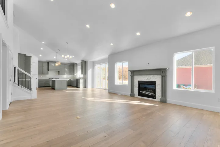 Open-concept living space featuring light wood-finish flooring, recessed lighting, and a contemporary fireplace with a white tile surround and grey mantel