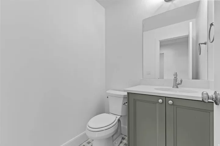 Vanity with light gray shaker-style cabinetry, white countertop, and integrated sink