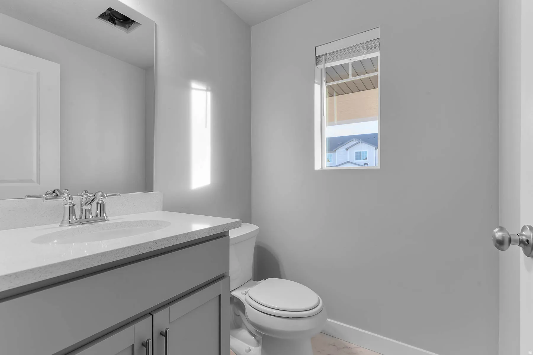 Modern bathroom featuring a single vanity with a light gray cabinet, white countertop, and chrome faucet