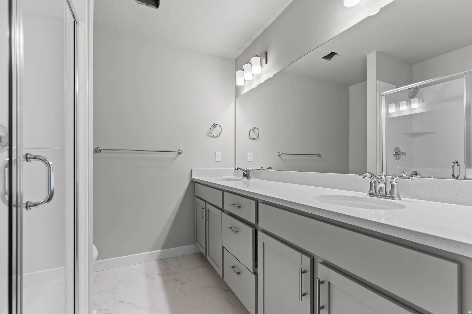 Dual vanity with integrated sinks, polished chrome fixtures, and a spacious mirror