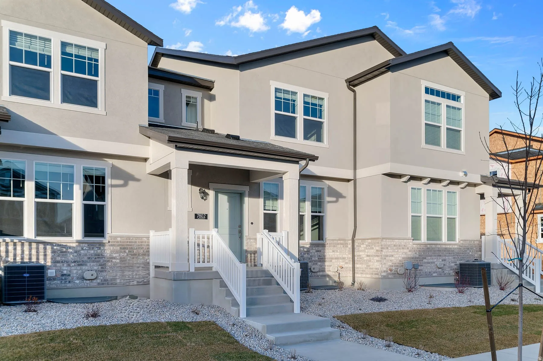 Contemporary townhome exterior featuring light stucco siding and a light brick facade