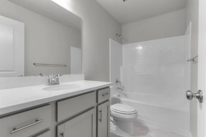 Bathroom featuring a vanity with an integrated sink, light-colored countertop, and gray shaker-style cabinetry