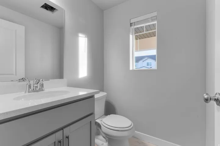 Modern bathroom featuring a single vanity with a light gray cabinet, white countertop, and chrome faucet