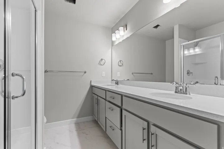 Dual vanity with integrated sinks, polished chrome fixtures, and a spacious mirror
