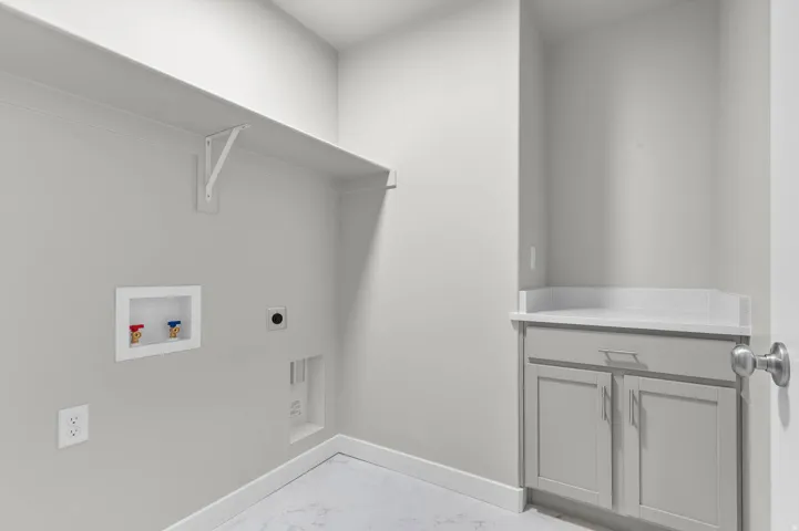 Dedicated laundry area featuring a built-in shelf, light gray cabinetry, a white countertop, and a utility sink rough-in