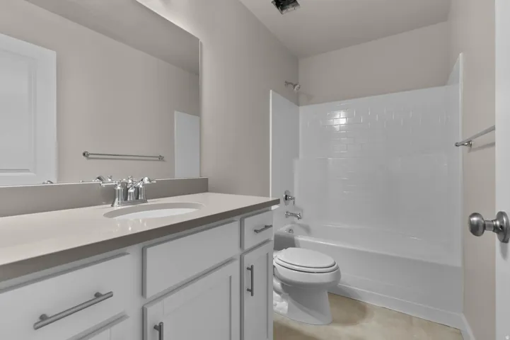 Bathroom featuring a white vanity with shaker-style cabinetry, a built-in sink, and a light-toned countertop