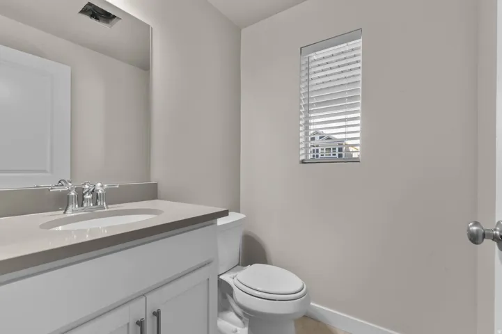 Vanity featuring a light countertop with an integrated sink and chrome faucet, white cabinetry, and a large wall-mounted mirror