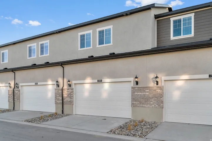 Multi-unit residential facade featuring light gray stucco and dark gray horizontal siding accents