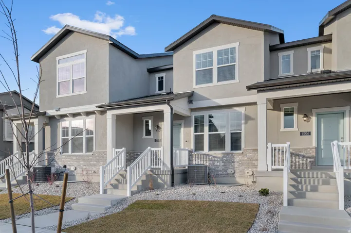 Contemporary townhome exterior featuring stucco siding and light brick accents