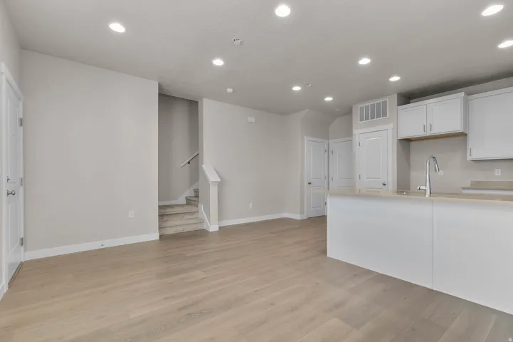 Open-concept living area with wood-finish flooring, recessed lighting, and a neutral color palette