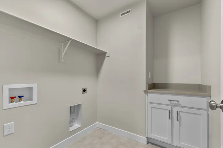 Dedicated laundry area featuring a wall-mounted shelf, built-in cabinetry, and countertop space