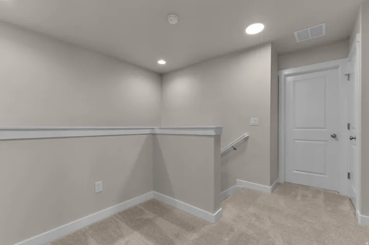 Carpeted landing with recessed lighting, chair rail molding, white trim, and a paneled interior door