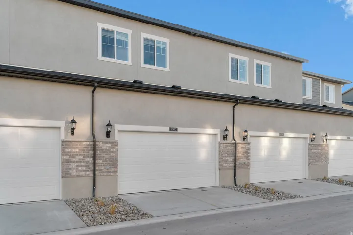 Exterior facade featuring two-car garages with white doors and concrete driveways