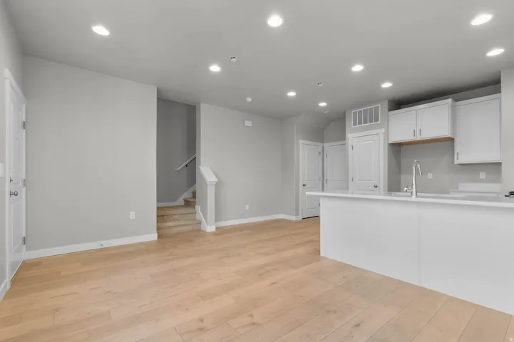 Open-concept living area featuring wood-finish flooring, recessed lighting, and a neutral color palette