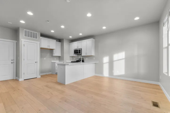 Open-concept kitchen and living area featuring light wood-finish flooring