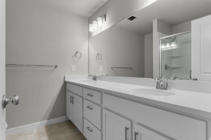 Double vanity with white cabinetry and integrated sinks, complemented by chrome fixtures