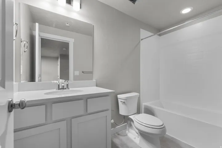 Bathroom featuring a white vanity with integrated sink, rectangular mirror, and three-light bar fixture