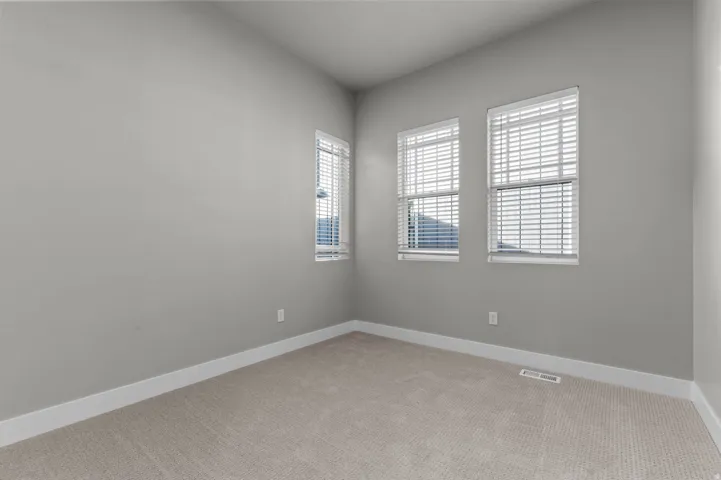 Interior room featuring light gray wall paint, white trim, and neutral carpet flooring