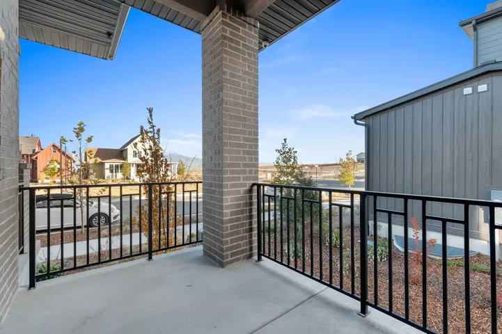 Exterior balcony featuring a concrete floor, black metal railing, and brick column
