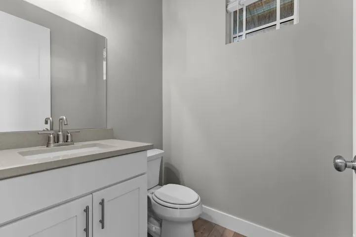 Bathroom featuring a white vanity with a light-toned countertop, an integrated sink with a brushed nickel faucet, and a large wall mirror