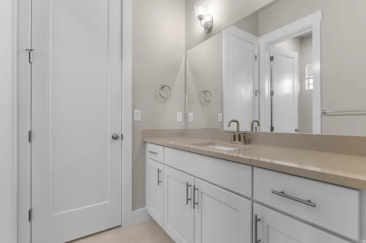 Bathroom vanity featuring a light-toned countertop, integrated sink, and brushed nickel faucet