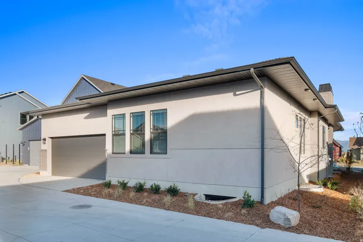 Contemporary exterior featuring stucco siding, a dark garage door, and a black roof
